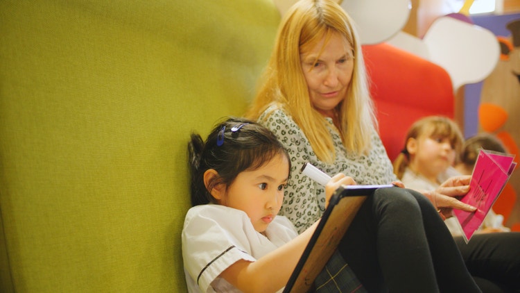 Students and teacher on comfortable chair writing on whiteboards