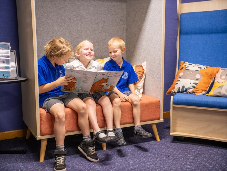 Three kindergarten children reading and smiling