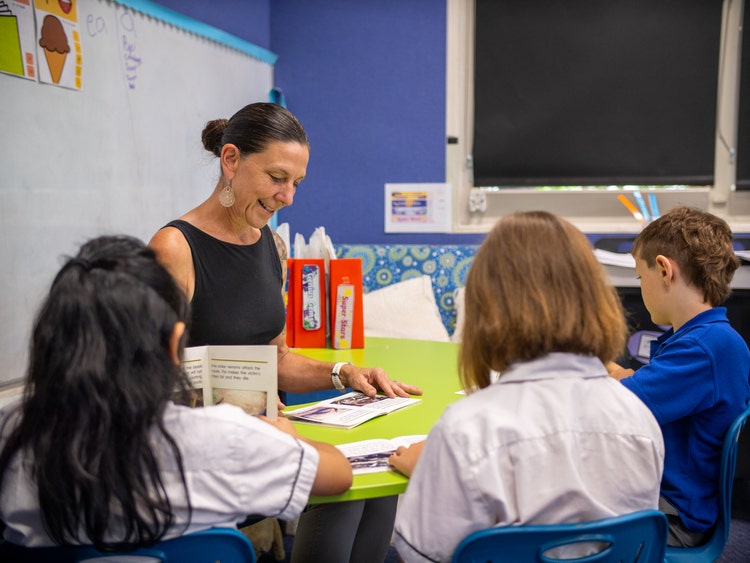 Teacher sitting with children in reading groups